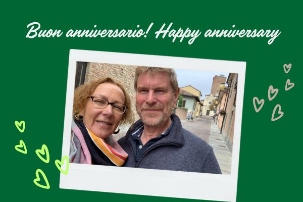 Coppia sorridente che festeggia l’anniversario passeggiando in un borgo piemontese